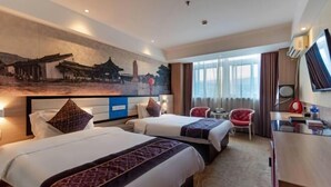 A hotel room with two beds, a desk, a chair, a painting on the wall, and a large window.