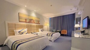A hotel room with two beds, a desk, a television, and a painting on the wall.