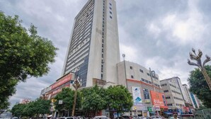 A tall building with multiple floors, surrounded by trees and other buildings.