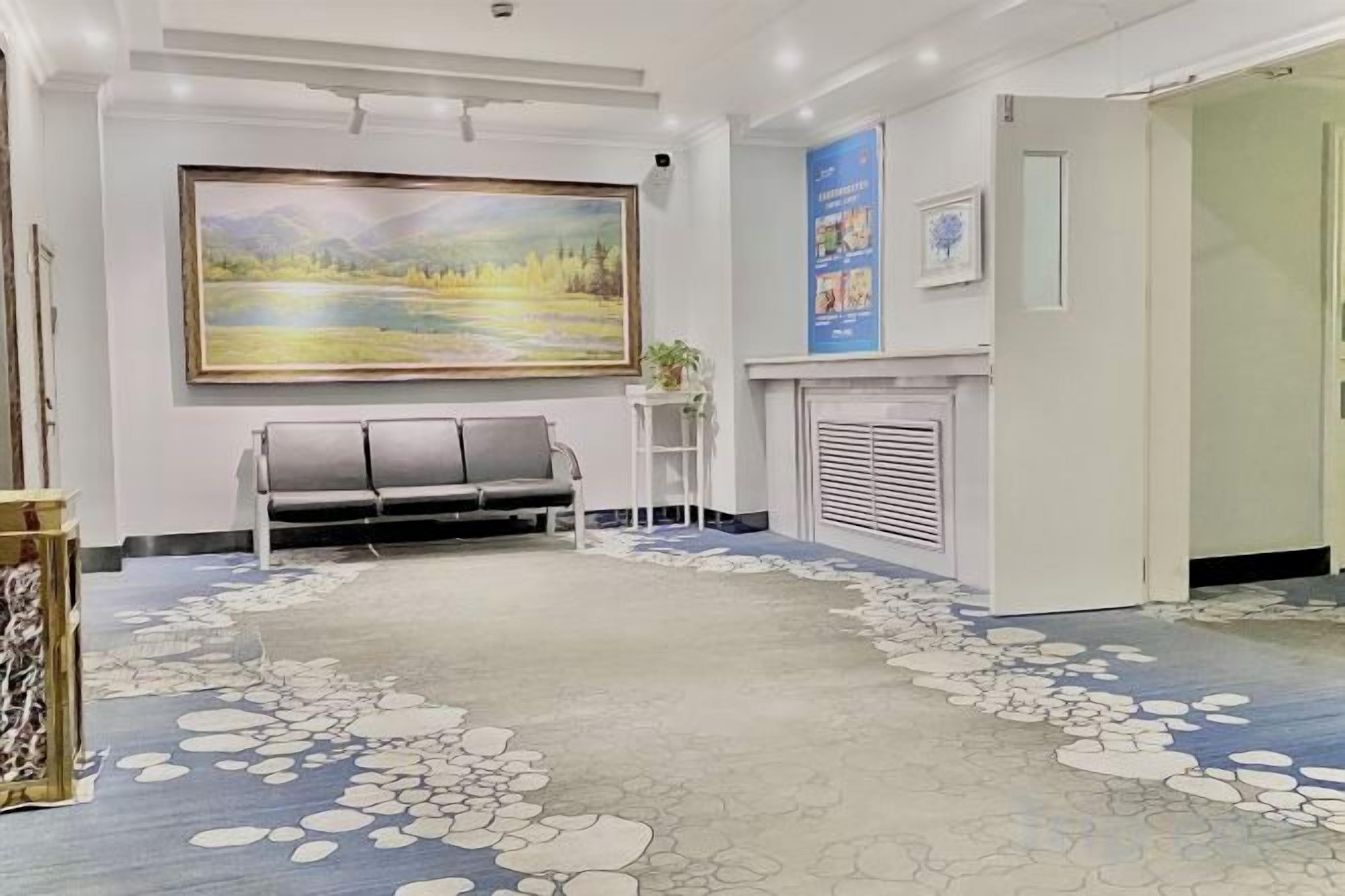 A reception area with a large painting, a seating area, and a patterned floor.