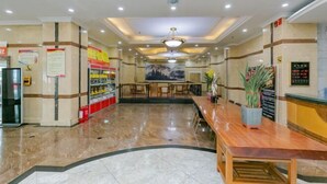 A hotel lobby with a reception desk, seating area, and a large mural on the wall.