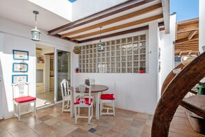 A patio with a table and chairs, a hanging lantern, and a window with a grid pattern. - Vacation Villa 'Fae' with Private Pool, Private Terrace and Wi-Fi (Playa Blanca)