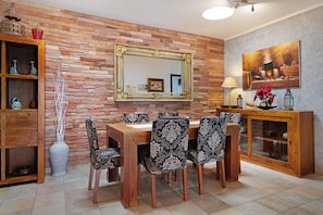 A dining area with a wooden table, patterned chairs, a mirror, and a cabinet with glass doors. - Vacation Villa 'Fae' with Private Pool, Private Terrace and Wi-Fi (Playa Blanca)