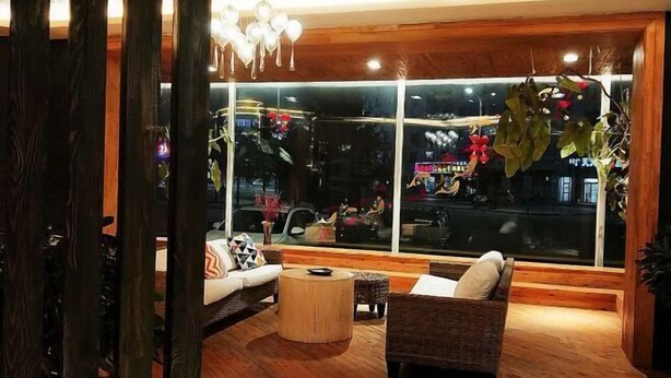 A cozy living room with a large window, wooden flooring, and a wicker sofa. - Jiuduo Holiday Hotel (Arun Banner)