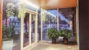 A hotel entrance with glass doors, indoor plants, and a view of the street outside. - Jiuduo Holiday Hotel (Arun Banner)