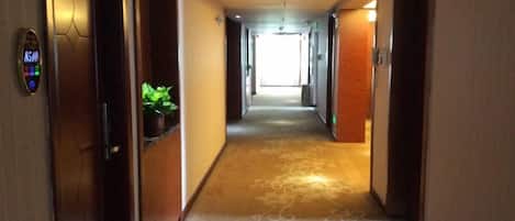En hotelgang med tæppe på gulvet, en receptionsdisk og døre til værelser.