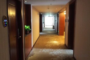 Ein Hotelgang mit Teppichboden, einem Empfangstresen und Türen zu Zimmern.