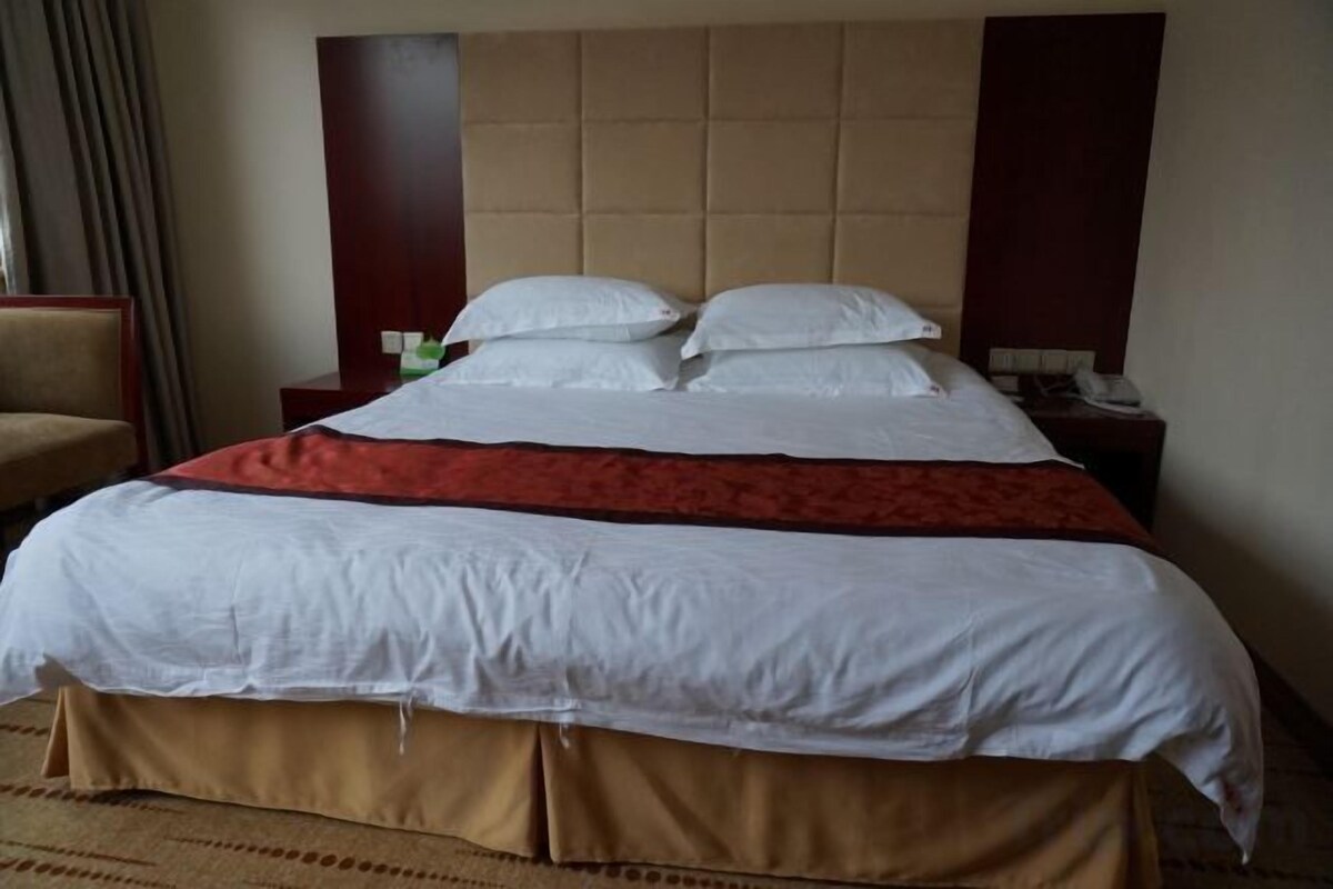 A hotel room with a large bed, a headboard, a nightstand, and a chair.