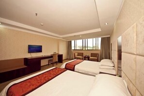 Habitación de hotel con dos camas, un escritorio, un televisor y una ventana con cortinas.