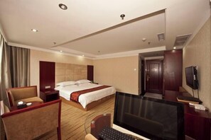 Una habitación de hotel con una cama, un escritorio con una computadora, una silla y un televisor.