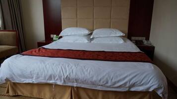 A hotel room with a large bed, a headboard, a nightstand, and a chair.