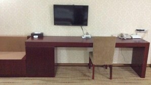A room with a flat-screen TV mounted on the wall, a wooden desk with a chair, and a telephone. - Lijing Hostel (Fuzhou)