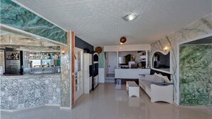 Um interior moderno com área de bar, cozinha e espaço para sentar.