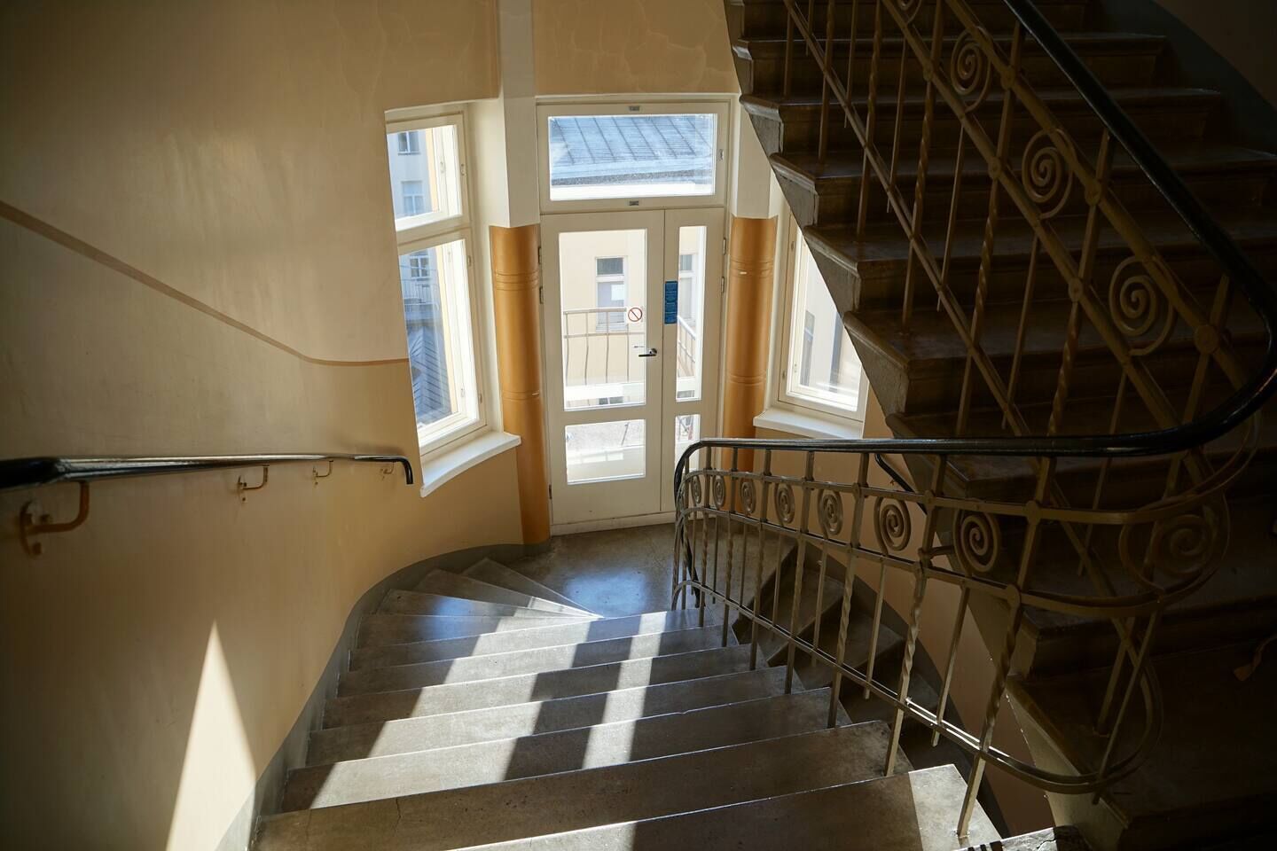 A staircase with a metal railing leading to a door with windows.