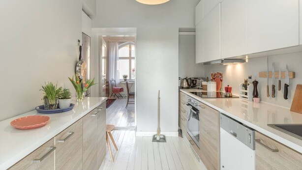 A modern kitchen with white cabinets, a central island, and a dining area in the background.