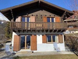 A two-story chalet with a balcony, wooden shutters, and a garage door. - Phipalo by Interhome (Ovronnaz)