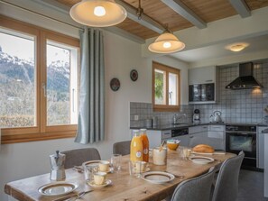 A modern kitchen with a dining area, large windows, and a view of mountains. - Phipalo by Interhome (Ovronnaz)