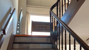 Una escalera de madera con barandilla y vista a una habitación con alfombra estampada.