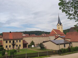 A traditional European village with a prominent church featuring a tall steeple and a clock tower. - Family -ONLY- welcome to Berching (Berching)