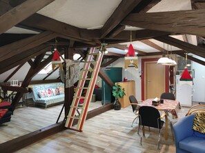 A loft-style room with exposed wooden beams, a wooden ladder, a dining table with chairs, and a sofa. - Family -ONLY- welcome to Berching (Berching)