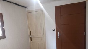 A room with a wooden floor, a white door with a handle, and a brown door with a handle. - Apartment by the river with snow peak views (Modane)