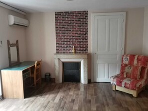 A room with a fireplace, a door, a desk, and a chair.