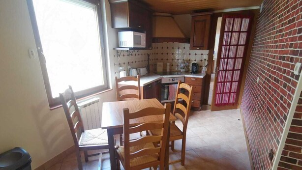 A compact kitchen with a dining table and chairs, a microwave, and a brick wall. - Apartment by the river with snow peak views (Modane)