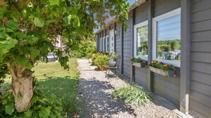 Ein Haus mit Kiesweg, Kübelpflanzen und Blumenkästen unter dem Fenster.