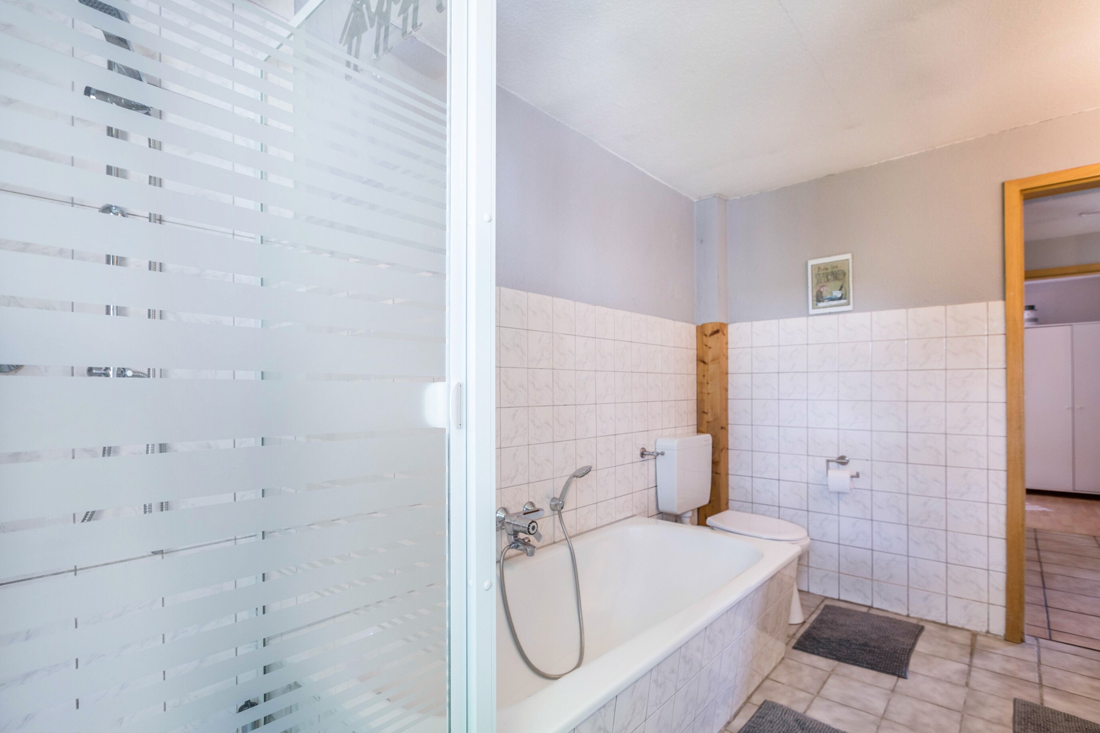 A bathroom with a glass shower enclosure, a bathtub, and a toilet.