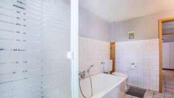 A bathroom with a glass shower enclosure, a bathtub, and a toilet.