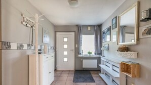 Ein Badezimmer mit einem weißen Waschbecken, Spiegel, Schrank, Handtuchhalter und einem Fenster mit Vorhängen.