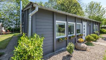 En etagers bygning med grå facade, store vinduer og indkørsel med grus.