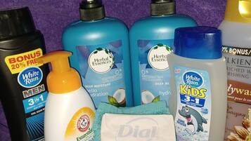 A variety of personal care products including shampoos, conditioners, and body wash on a purple towel.