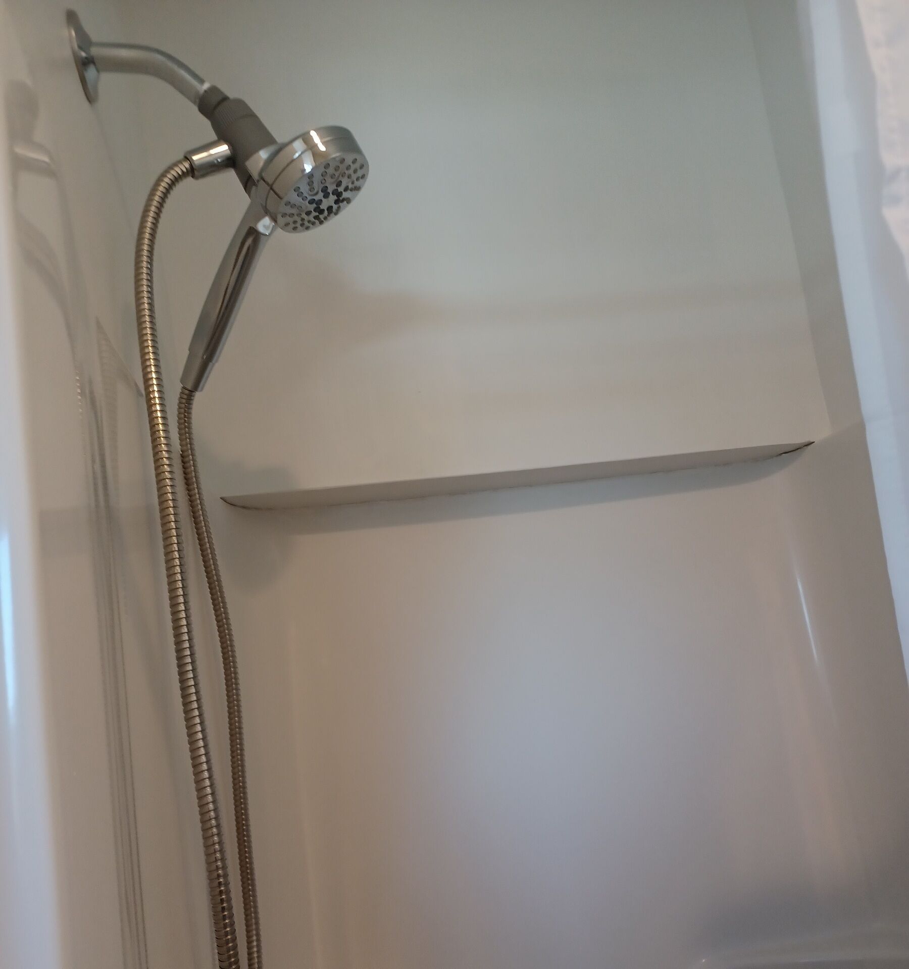 A showerhead with a flexible hose, a control knob, and a wall-mounted shower control panel.