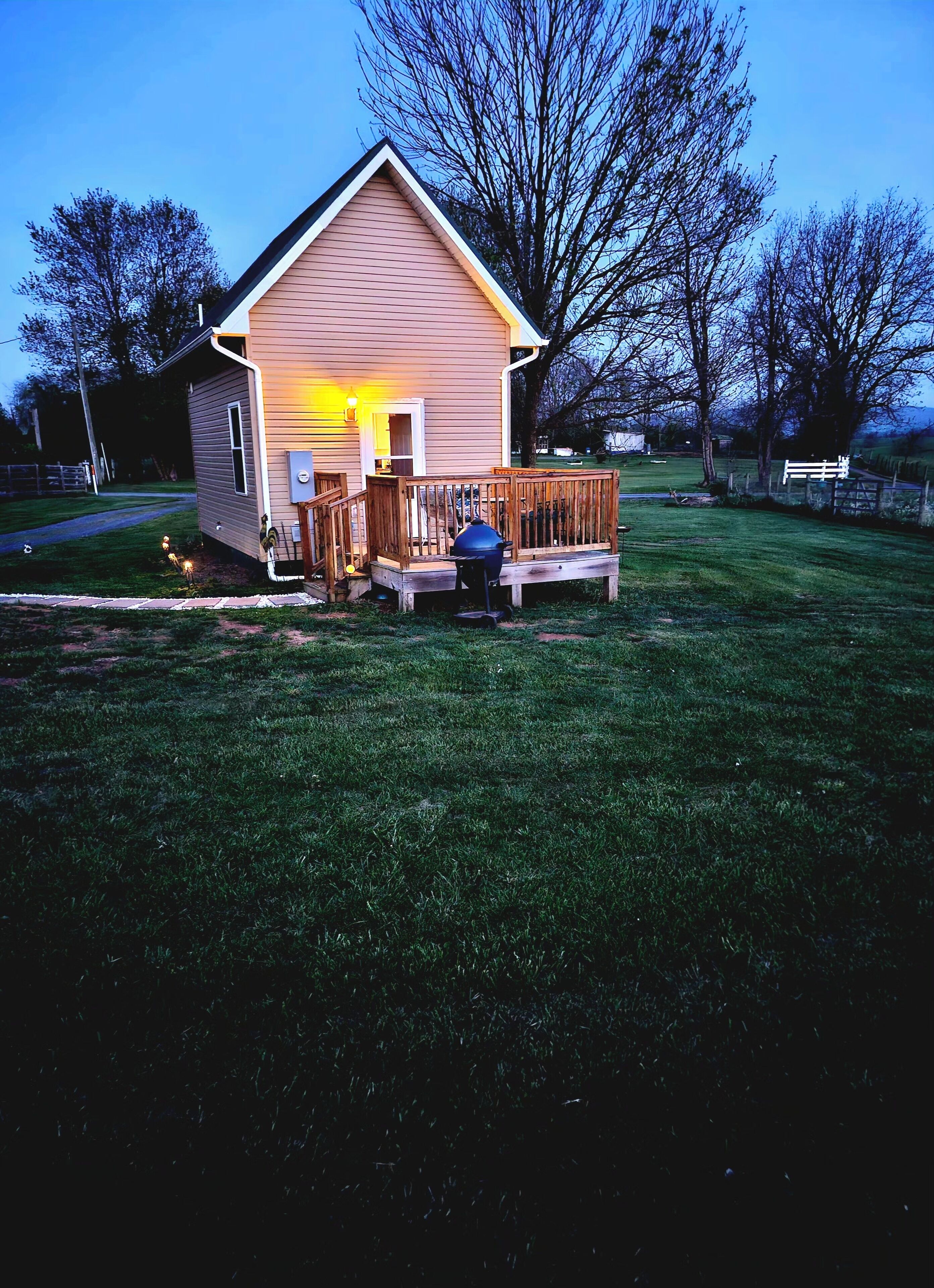 Une petite maison avec une terrasse en bois et un barbecue à l’avant.