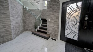 A modern interior with a staircase, a glass railing, and a decorative door. - 6 bdrm home w pool/hot tub/pool table/bar/kareoke (Surrey)