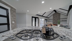 A modern kitchen with a gas stove, granite countertop, and a kettle. - 6 bdrm home w pool/hot tub/pool table/bar/kareoke (Surrey)