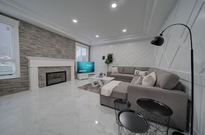 Un salon moderne avec une cheminée, un téléviseur à écran plat, un canapé gris et une table basse.