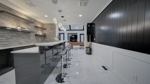 A modern kitchen with a central island, bar stools, and pendant lighting. - 6 bdrm home w pool/hot tub/pool table/bar/kareoke (Surrey)