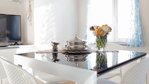 A dining table with a vase of flowers, a decorative tray, and a small plant. - Vacation Apartment in the Historic Center with Sea View and Shared Garden (Bordighera)