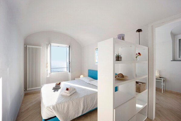 A bedroom with a bed, a white wardrobe, a window, and a radiator.