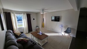 A living room with a sofa, coffee table, TV, and ceiling fan. - Furnished house in Geraldton (Geraldton)