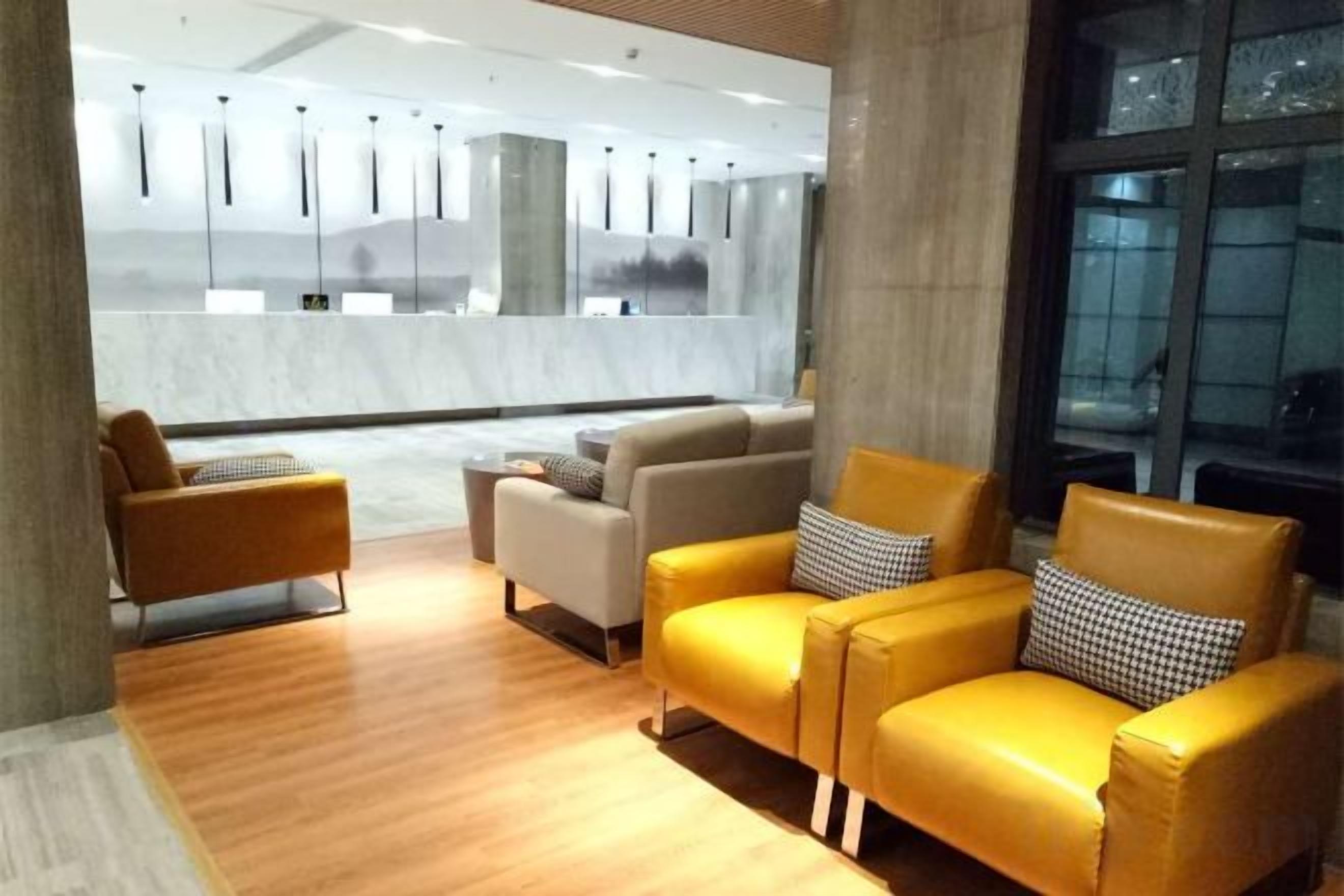 A modern lobby with leather sofas, a wooden floor, and a view of the reception area.