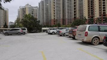 A parking lot with multiple cars parked in rows, surrounded by high-rise residential buildings.