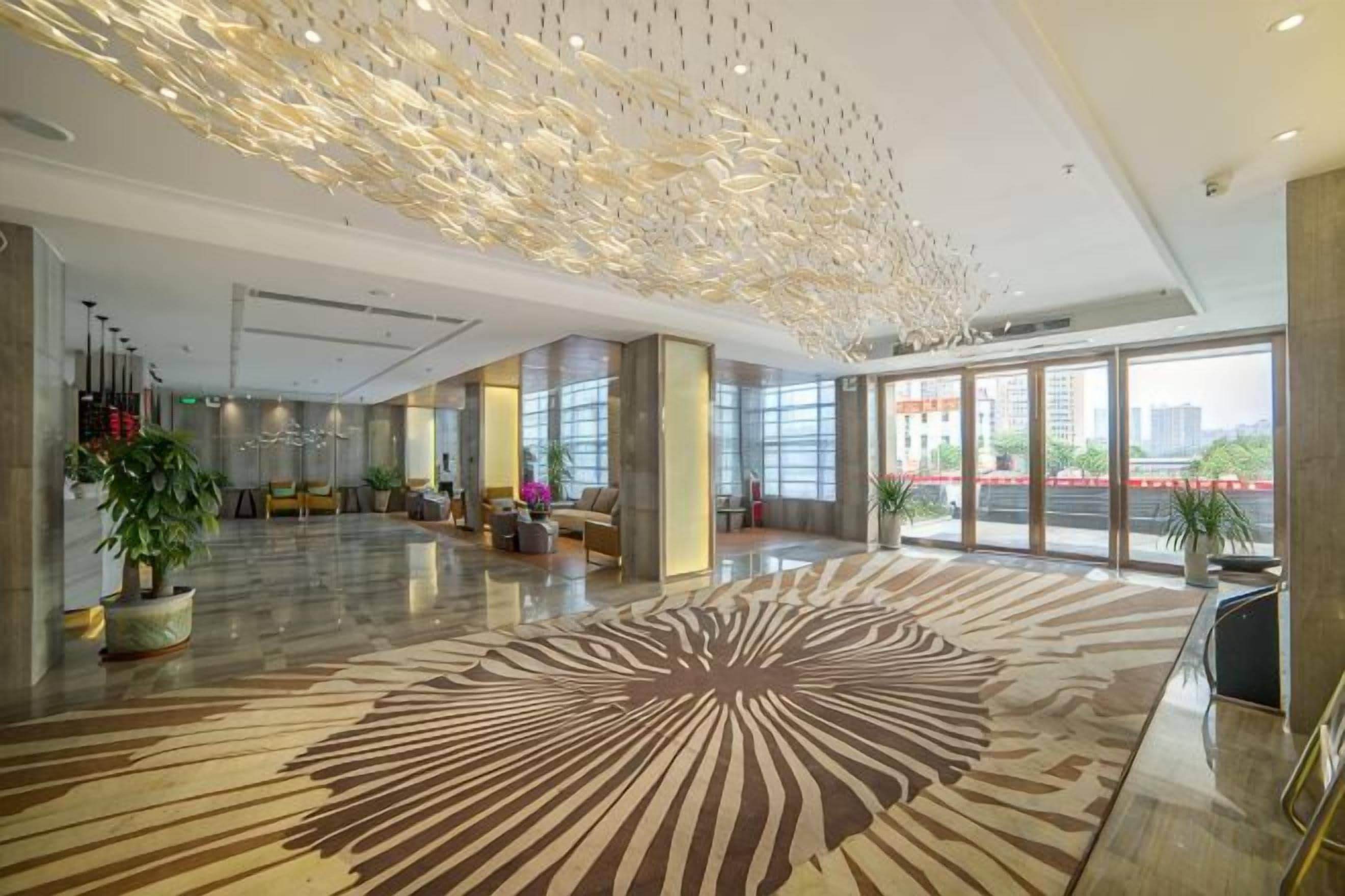 A spacious lobby with a patterned carpet, large windows, and a modern ceiling design.