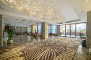 A spacious lobby with a patterned carpet, large windows, and a modern ceiling design. - Shuang Yi Hotel (Huizhou)