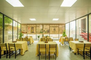 A dining area with tables and chairs, large windows, and a staircase. - Shuang Yi Hotel (Huizhou)