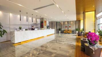 A hotel reception area with a marble counter, a receptionist, and a reception desk.