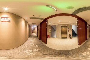 A hotel corridor with a curved ceiling, a carpeted floor, and a sign on the wall. - Shuang Yi Hotel (Huizhou)