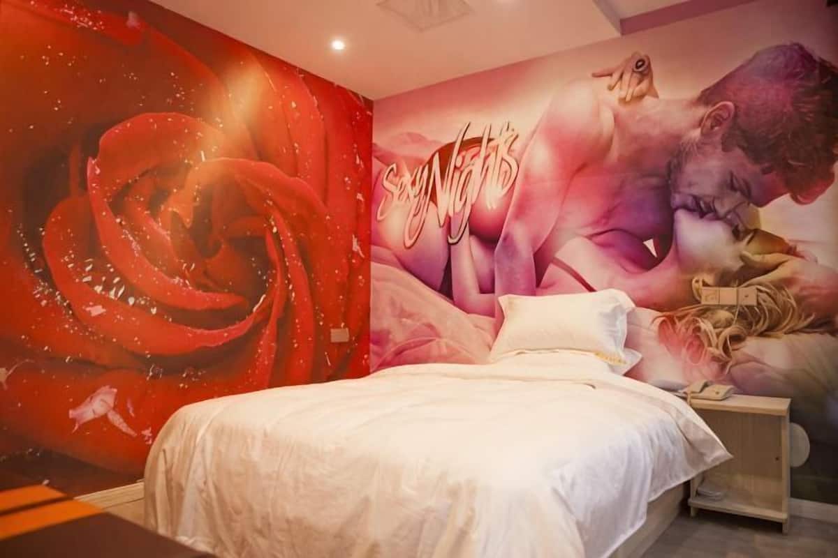 Un dormitorio con una cama grande, una mesita de noche y un mural en la pared.